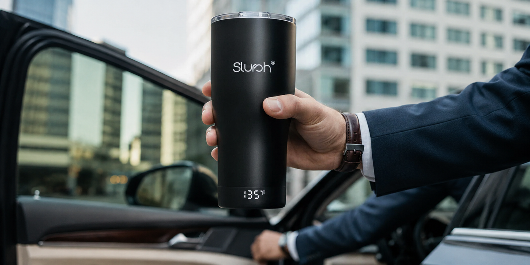 A commuter holds the Smart Temperature Control Tumbler beside a car